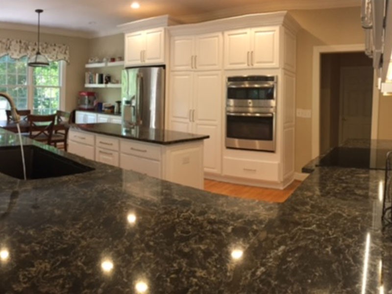 Remodeled kitchen with white cabinets and black granite countertops